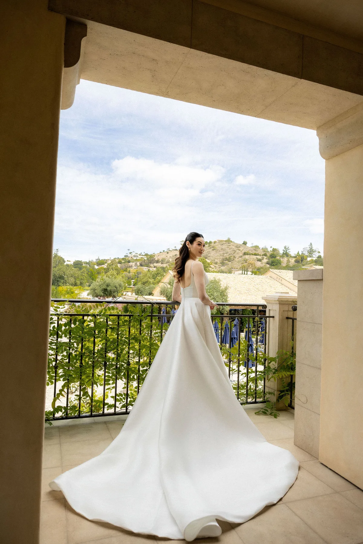 The bride seen through a stone arch on the loggia, hills beyond