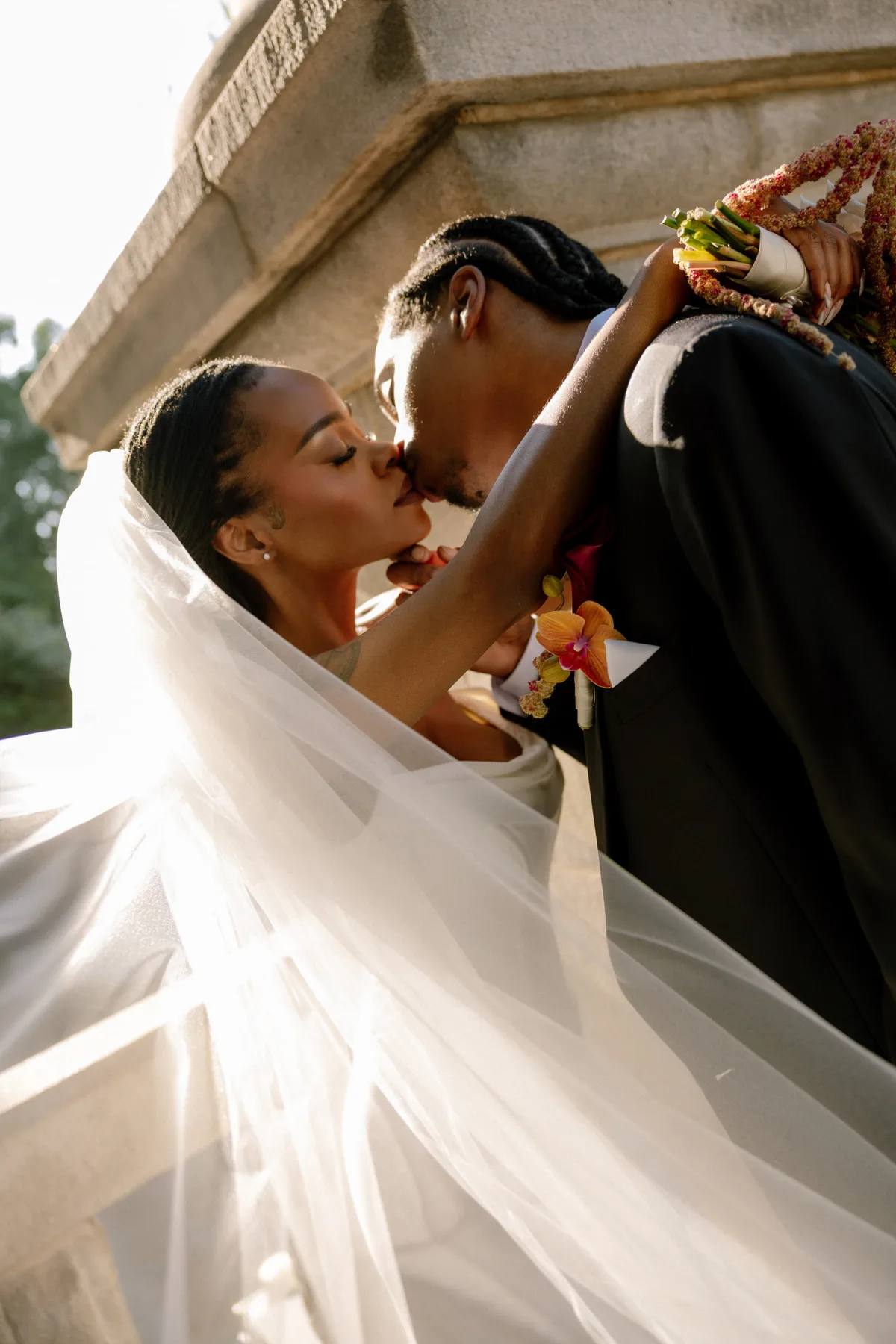 A couple kissing under the bride's veil in low sun